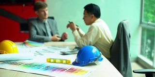 建筑师和工程师开会计划一个新项目，建筑设备摆在桌上。