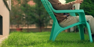老人坐在塑料椅子上在户外看书
