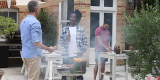 三个男人站在花园里烧烤，笑着