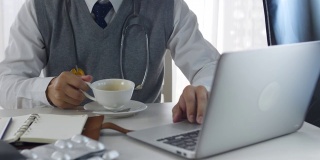 医生使用手提电脑和喝咖啡