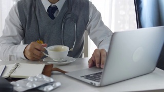 医生使用手提电脑和喝咖啡视频素材模板下载