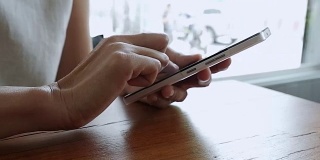 在咖啡厅喝咖啡或喝茶时，用手机拉近手。一个女人在咖啡店里用智能手机浏览图片。