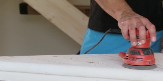 木匠打磨一个木制台阶与电动砂光机车间特写