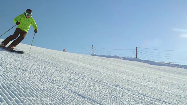 慢动作跟踪完美的雪道与滑雪者雕刻下斜坡