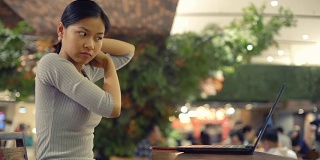 漂亮的亚洲女孩用笔记本电脑梳理她的头发前视频电话