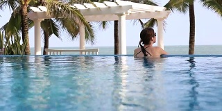 旅行电影的女人放松在热带度假无限泳池