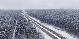 4 k。在冬天的森林里开着车在下雪。空中全景。消失点的角度来看