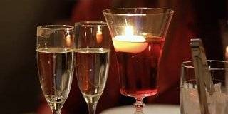 两杯香槟和桌上点着蜡烛的杯子
