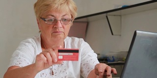 一位上了年纪的妇女在网上输入信用卡数据进行购买