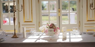 节日的餐桌上摆放着玻璃杯和鲜花，在阳光的照射下近距离观看。优雅的餐具与烛台安排在餐厅晚餐或午餐吃。精致餐饮婚宴餐饮