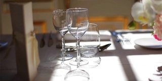 菜单上的单杯空酒，水和粉红色的鲜花花束在白色桌布上安排精致的餐饮跟踪微距特写。节日优雅的餐桌，在餐厅，咖啡厅宴会上用餐