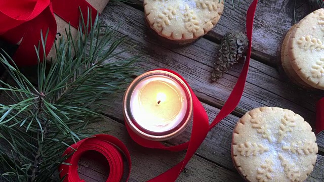 特写燃烧的白色蜡烛和圣诞肉馅饼在质朴的木头桌子上。概念的冬季假期和圣诞烘焙。前视图。