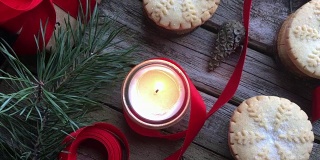 特写燃烧的白色蜡烛和圣诞肉馅饼在质朴的木头桌子上。概念的冬季假期和圣诞烘焙。前视图。