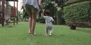 可爱的小男孩和妈妈在草地上迈出了第一步