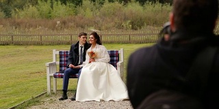 一对新婚夫妇在长凳上对着摄影师摆姿势