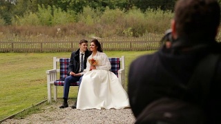 一对新婚夫妇在长凳上对着摄影师摆姿势视频素材模板下载