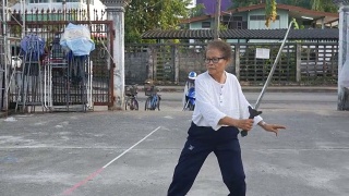 一位老妇人在停车场练习中国剑舞视频素材模板下载