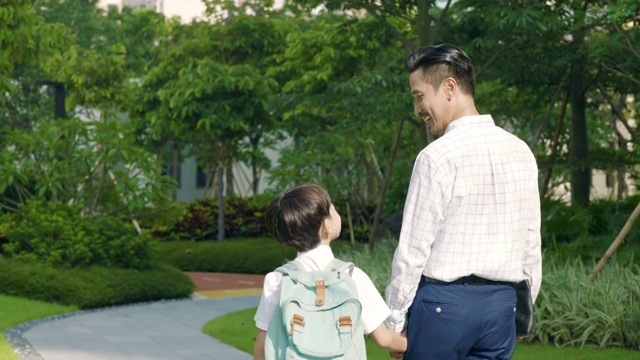 亚洲父子并排上学的后视图慢镜头