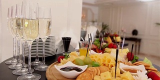 在自助餐桌上，在餐厅或酒店大堂的自助餐桌上，配有香槟和水果的玻璃杯，镜头沿着，景深浅，在餐厅大堂欢迎客人