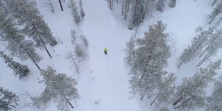 航拍:一个不认识的人走在白雪覆盖的路上穿过神秘的森林