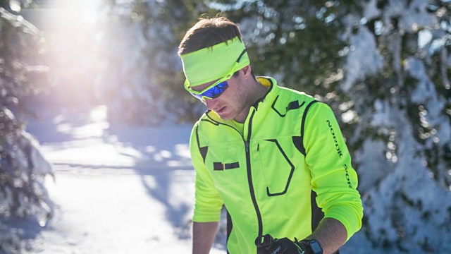 男运动员在冬季景观，查看智能手表