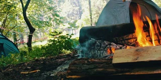 在旅游帐篷的背景中，燃烧着的火和木头