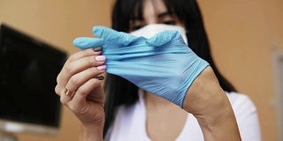 女性医生的手戴乳胶手套的特写。不认识的护士在外科口罩敷药手套，而坐在桌子在她的办公室。在4 k拍摄