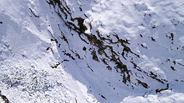 高空飞过雪山，山脊，山谷建立者向前飞行。户外雪高山野生自然景观在冬季顶视图与阳光和阴影。4k无人机飞行建立镜头