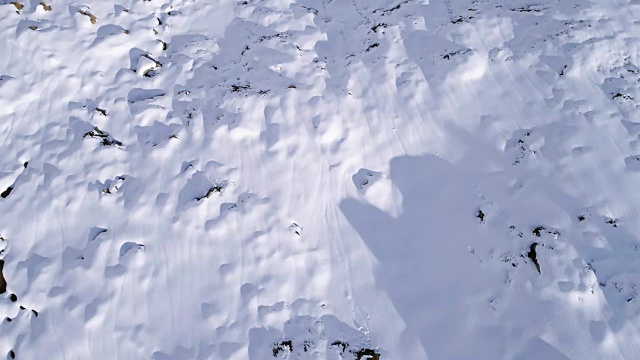 高空飞过雪山，山脊，山谷建立者向前飞行。户外雪高山野生自然景观在冬季顶视图与阳光和阴影。4k无人机飞行建立镜头