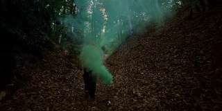 人在森林中持有绿色烟雾- 4K分辨率