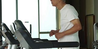 亚洲老年人在健身房的跑步机上跑步，锻炼健康的生活方式