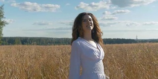 一个穿着白色裙子的歌手正在麦田里唱歌。