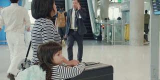 亚洲母亲和她的女儿在机场寻找航班时间