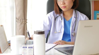 女医生用笔记本电脑在写字板上做笔记视频素材模板下载