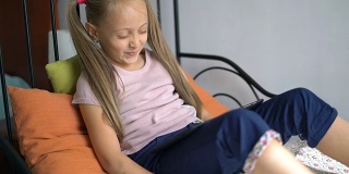 小女孩在家里玩数码平板电脑。