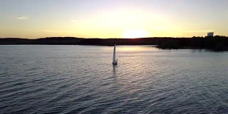 令人惊叹的日落颜色。河面上漂浮着帆船的剪影。