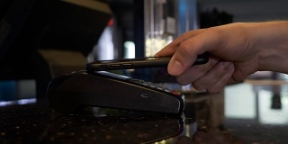 顾客在酒吧使用智能手机和pos支付服务