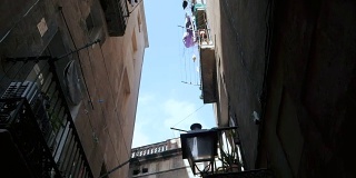 斯坦尼康镜头拍摄:在巴塞罗那的哥特式地区带阳台的房子。巴塞罗那狭窄街道上的老房子的正面。旅行的概念。慢动作