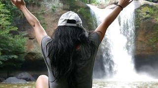 年轻女子在瀑布前伸出双臂视频素材模板下载
