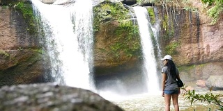年轻的亚洲女游客站在瀑布前