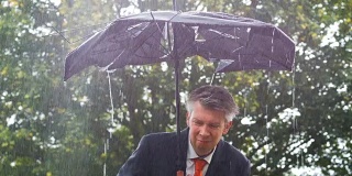 一个商人在雨中躲在一把破伞下