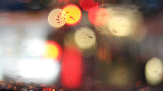 雨点落在挡风玻璃上，车辆在交通堵塞时发出模糊的光