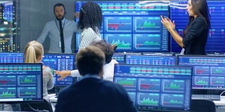 多族裔交易员团队在证券交易所办公室度过成功的一天。交易商和经纪人在市场上买卖股票，他们庆祝有利可图的交易。显示器显示相关的信息图，数据和数字。
