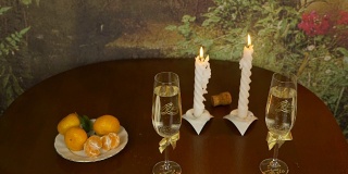 新婚夫妇的浪漫餐桌。两杯起泡酒。两根蜡烛是热的。泡沫在酒杯里闪闪发光。男人吹灭了蜡烛。一股烟升起来。