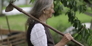 一个肩上扛着锄头的老妇人的肖像。