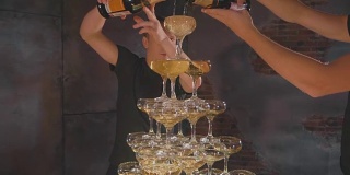 侍者倒香槟在杯子在金字塔的慢动作，特写