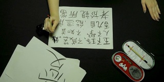 女性用毛笔和墨水在宣纸上书写中国书法。写书法的时候，手握毛笔的时候要靠近。中国书画