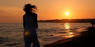 日落时分在海滩上跑步:女人独自跑步——慢镜头