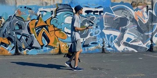 一名男性涂鸦艺术家沿着一面墙走着。