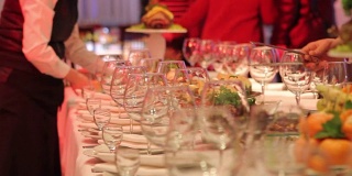 服务员在餐厅宴会桌上安排酒杯，空酒杯放在宴会桌上，新年、圣诞节